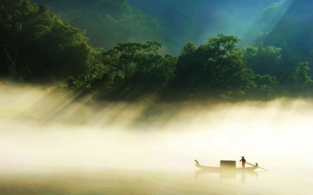 A serene China river scene with a boat gliding through morning mist near lush forested hills