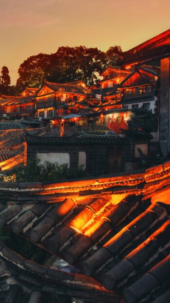 Traditional China architecture illuminated at sunset with ancient rooftops and trees in the background