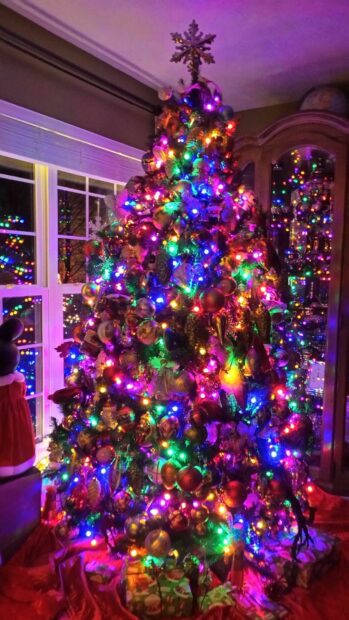 A colorful Christmas tree decorated with ornaments and bright lights indoors