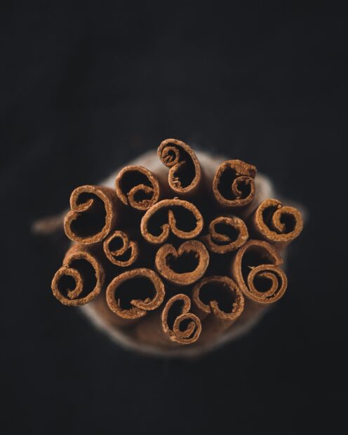 Close up view of cinnamon sticks arranged in a bundle on a dark background