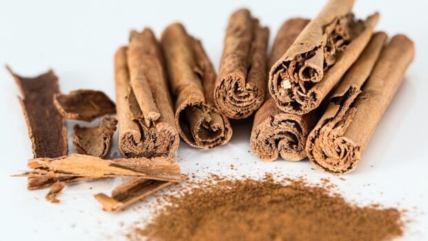 Close up of cinnamon sticks and ground cinnamon arranged on a white surface