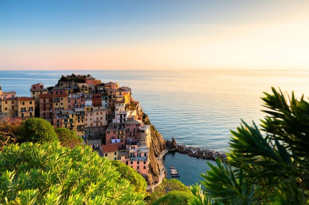 Colorful buildings stacked on the cliffs in Cinque Terre with a calm sea view