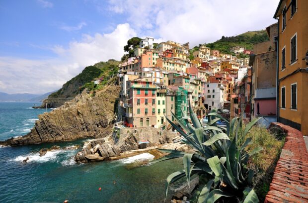 Colorful Cinque Terre town on rocky cliffs with clear sea and green plants in Italy