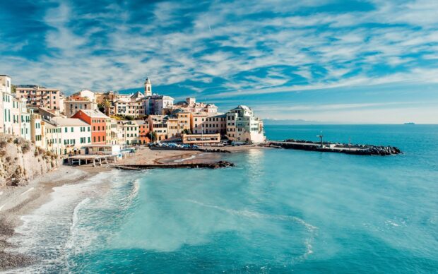 Colorful Cinque Terre village buildings along the seaside with clear blue water and sky clouds