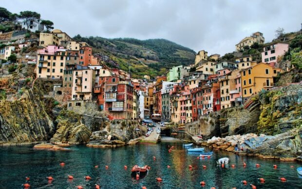 Colorful Cinque Terre village on rocky coastline with boats in the harbor