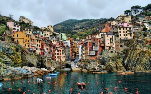 Colorful coastal town of Cinque Terre with boats and hills in the background