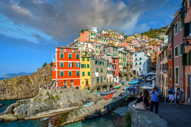 Colorful houses in Cinque Terre village along the rocky coastline under a cloudy sky