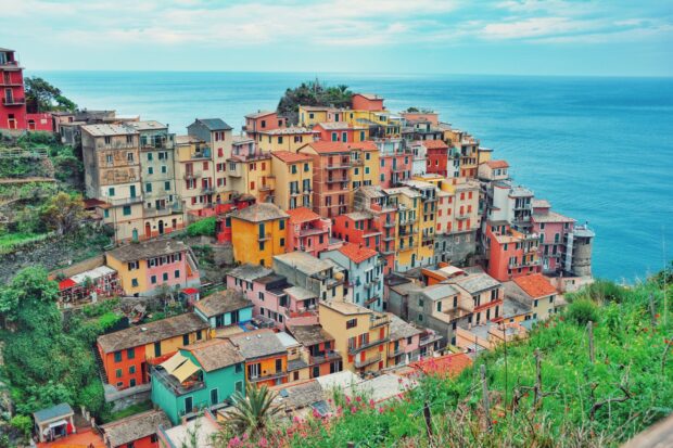 Colorful houses of Cinque Terre village by the sea with lush greenery and blue sky