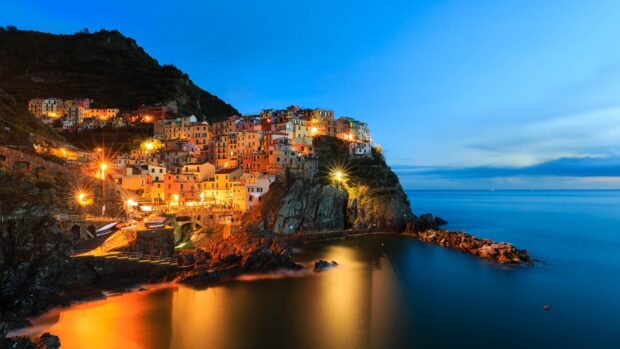 Colorful Cinque Terre village built on rocky cliffs by the sea at dusk