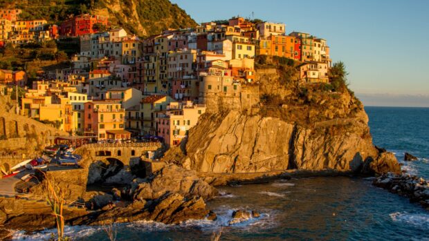 Colorful hillside town in Cinque Terre with steep cliffs and ocean views at sunset