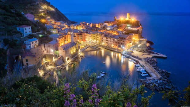 Night view of Cinque Terre village with illuminated buildings and harbor on the coast