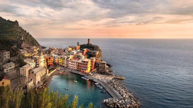 Colorful Cinque Terre village by the sea with clear water and rocky coastline at sunset