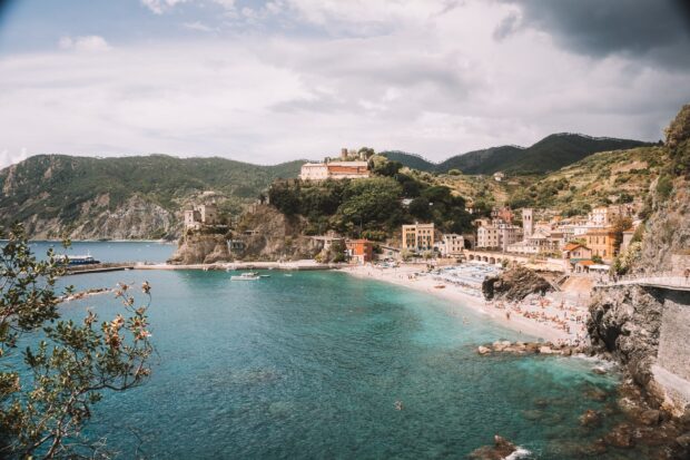 A scenic view of Cinque Terre coastal town with clear water and lush green hills