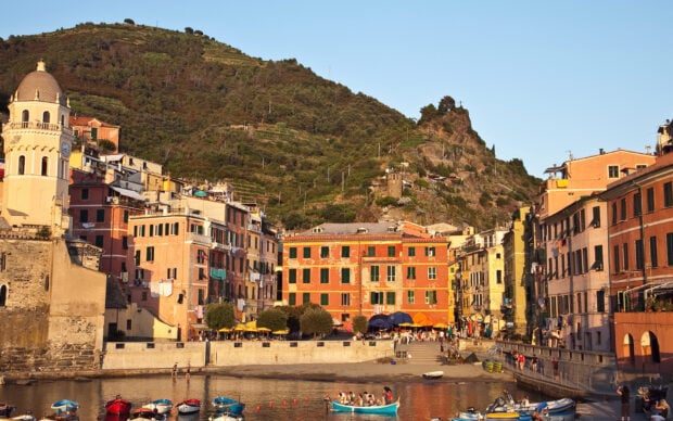 Colorful buildings of Cinque Terre with boats in the harbor and hills in the background