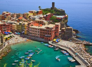 Colorful Cinque Terre town with boats docked in the turquoise sea bay