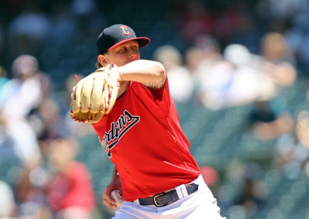 Cleveland Guardians player pitching the ball during a baseball game in a red uniform