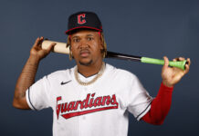 Cleveland Guardians player posing with a baseball bat on his shoulder against a plain background