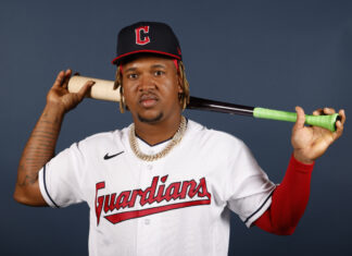 Cleveland Guardians player posing with a baseball bat on his shoulder against a plain background