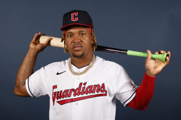 Cleveland Guardians player posing with a baseball bat on his shoulder against a plain background