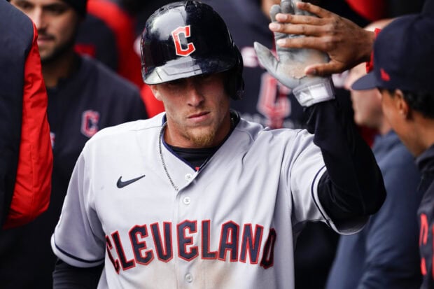 A Cleveland Guardians player wearing a helmet and jersey celebrates with teammates after a successful play