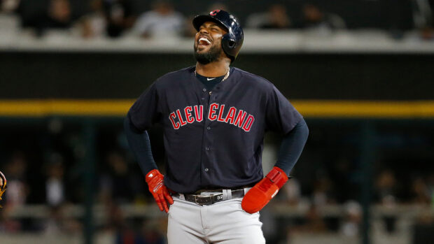 A Cleveland Guardians player smiling during a baseball game wearing team uniform and helmet