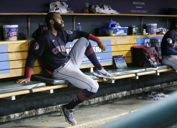 A Cleveland Guardians player sitting thoughtfully in the dugout during a game
