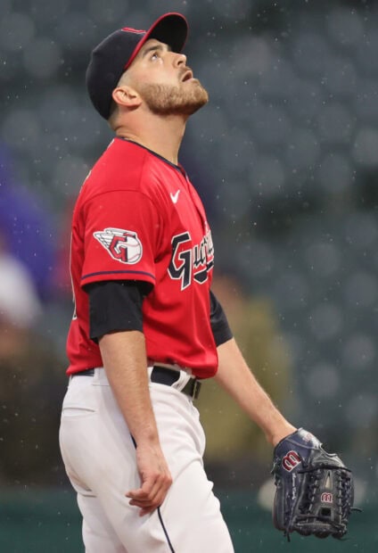 Cleveland Guardians player in uniform looking up during a game in the rain