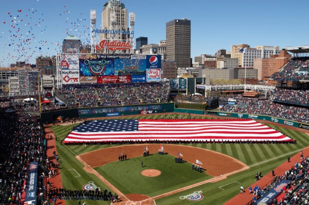 A Cleveland baseball stadium with a large American flag covering the field on Opening Day