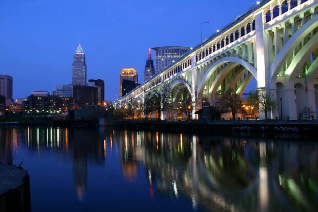 The Cleveland city skyline with illuminated bridge and river reflections at dusk