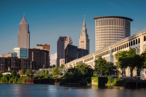The Cleveland skyline with iconic buildings and a bridge over the river in clear daylight