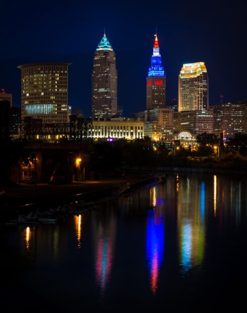 Nighttime Cleveland skyline with colorful lights reflecting on calm water