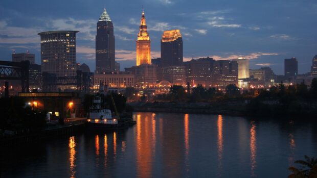 The Cleveland skyline at dusk with river reflections and city lights illuminating the buildings