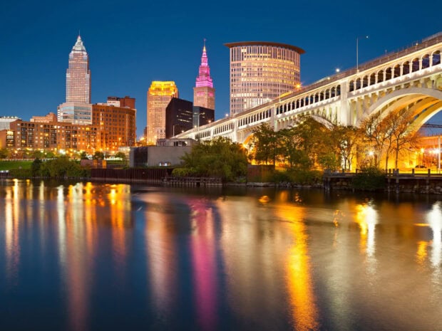 The Cleveland skyline with illuminated buildings and bridge reflecting on the river at night