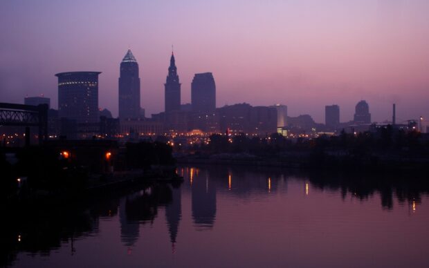 Cleveland city skyline reflecting on calm river at dusk with purple sky