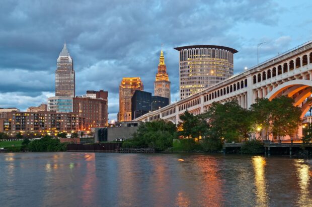 Cleveland skyline with famous landmarks reflected on the river under a cloudy sky