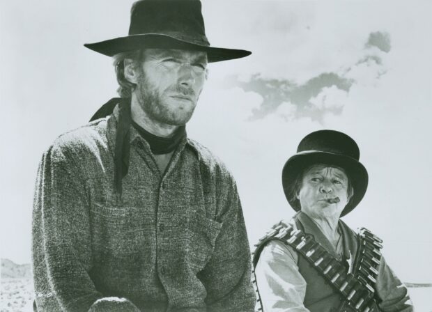 Clint Eastwood and a companion dressed as cowboys in a classic western scene