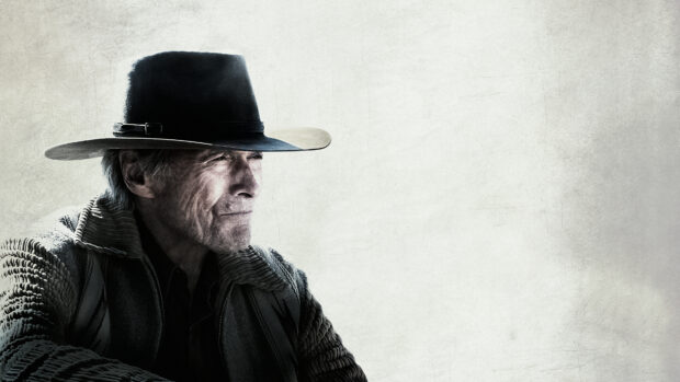 Clint Eastwood wearing a cowboy hat and patterned jacket looking thoughtfully to the side