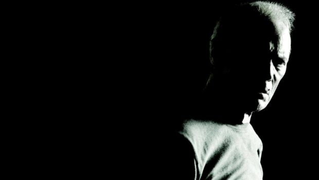 Clint Eastwood facing sideways in a dark setting with strong shadow contrasts