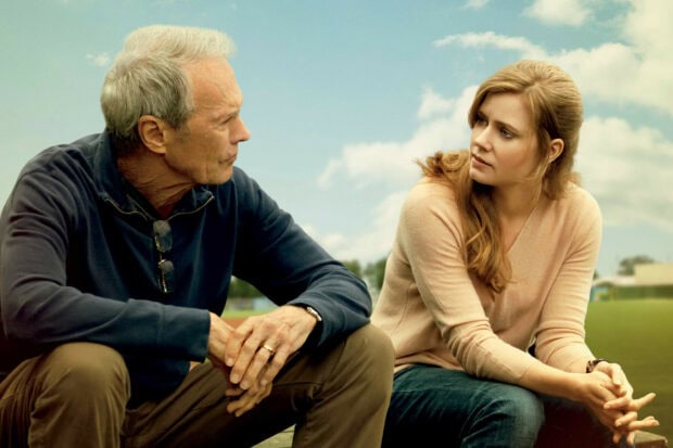 Clint Eastwood having a serious conversation with a woman outdoors in a casual setting