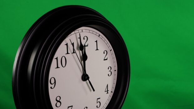 A classic clock showing time against a green background with clear black numbers and hands