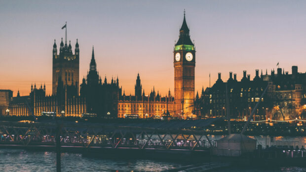 Big Ben clock tower is illuminated at dusk over the River Thames in London