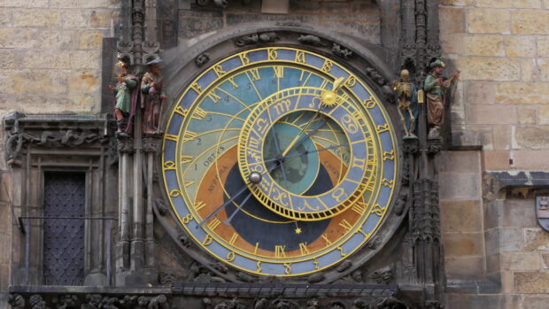 Historic clock with zodiac symbols on an ancient stone building facade