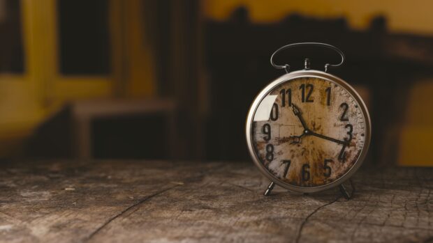 Vintage clock with rustic face on wooden surface in warm light
