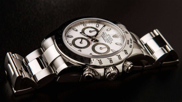 A close up of a luxury chronograph watch with a stainless steel bracelet on a dark surface