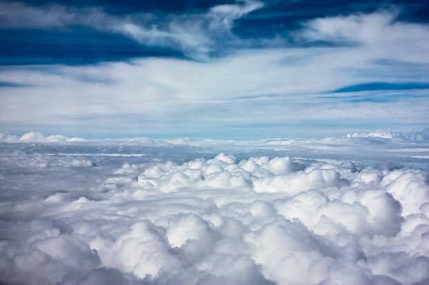 Fluffy clouds floating above the ocean of clouds under a bright blue sky