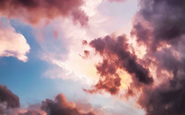 Pink and purple clouds forming a dramatic sky with soft light glowing through the clouds