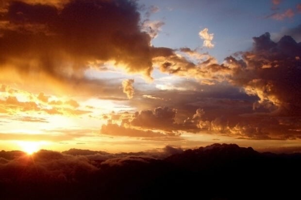 A dramatic clouds scene at sunset over a mountain range with colorful sky and clouds