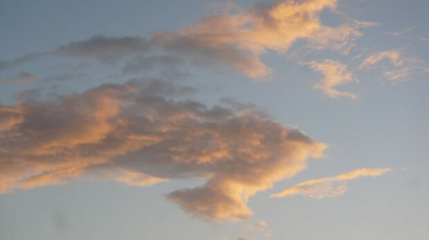 Soft clouds glowing with warm sunlight in a clear sky at dusk