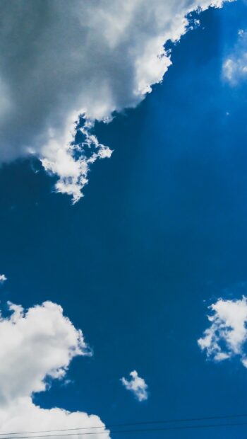 Fluffy clouds drifting across a deep blue sky in a calm clouds scene
