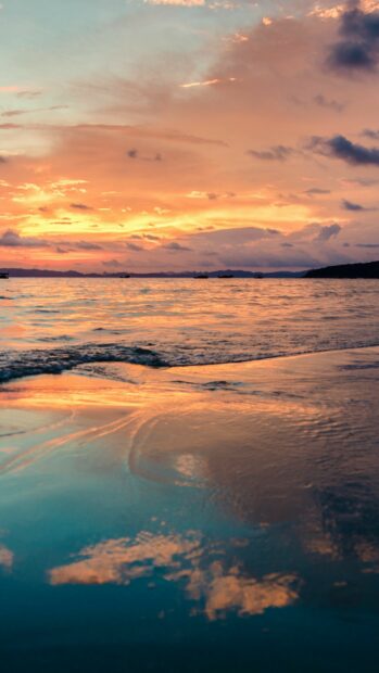 Soft clouds reflecting over calm ocean waters during a colorful sunset